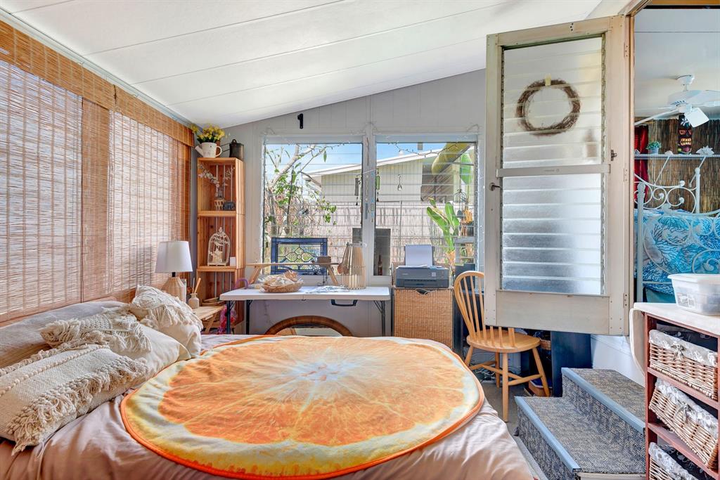 A bedroom with a bed featuring an orange slice blanket, a desk, and a screen door — 515 50TH AVENUE TERRACE W, BRADENTON, FL