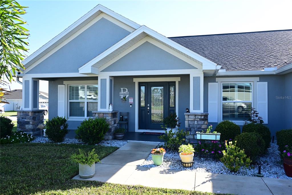 The front exterior of a single-story house features a stone-accented porch and blue siding — 891 GALLOWAY STREET, LAKE ALFRED, FL