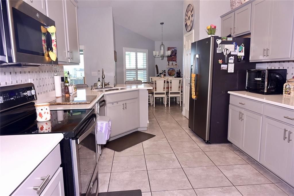 A kitchen with light gray cabinets, stainless steel appliances, and tile flooring — 891 GALLOWAY STREET, LAKE ALFRED, FL