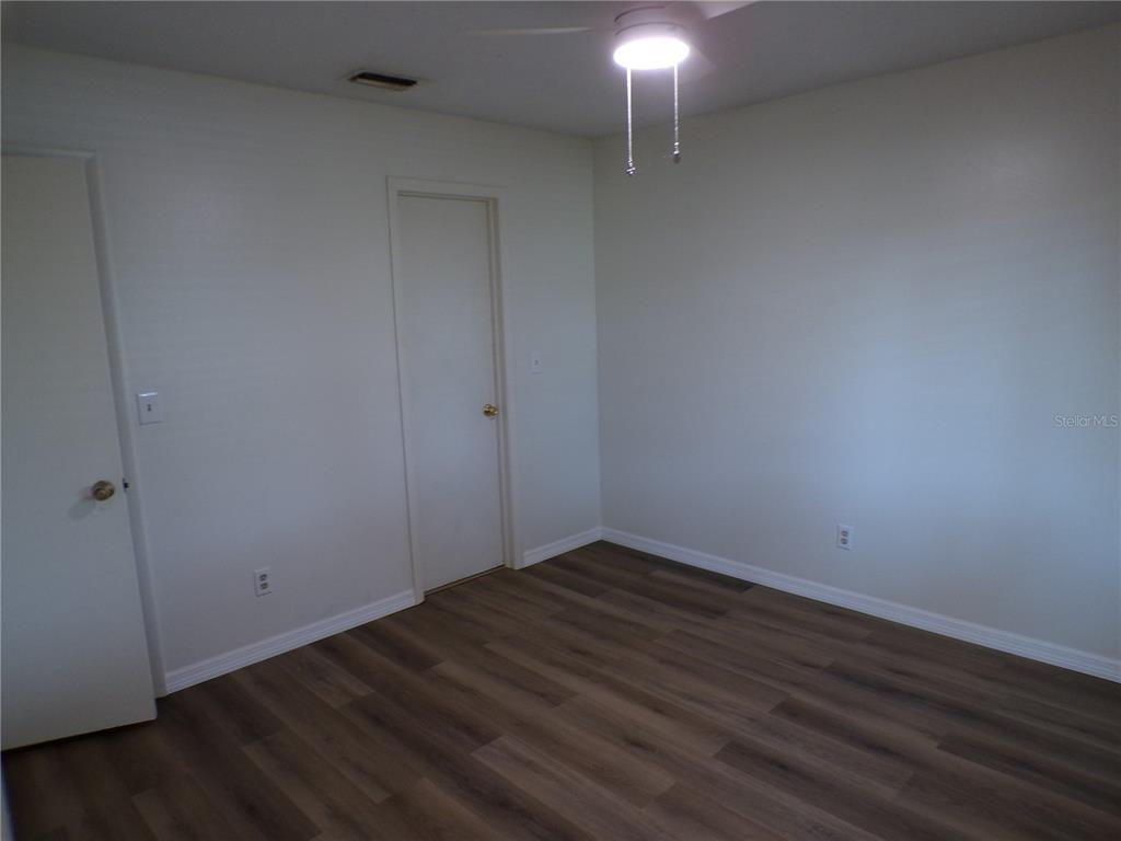 A spacious room with light-colored tile flooring, a vaulted ceiling, and sliding glass patio doors — 10104 WILLMINGTON BOULEVARD, ENGLEWOOD, FL