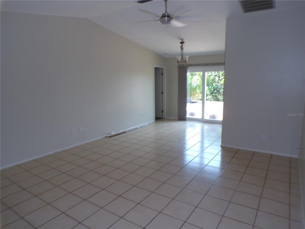 A kitchen features white cabinets, red countertops, white appliances, and light-colored tile flooring — 10104 WILLMINGTON BOULEVARD, ENGLEWOOD, FL