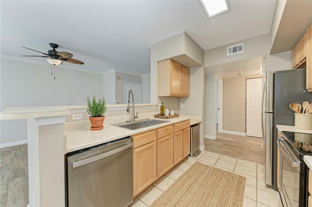 A kitchen with light wood cabinets, stainless steel appliances, and a breakfast bar counter — 1195 VILLAGIO CIRCLE UNIT 101, SARASOTA, FL