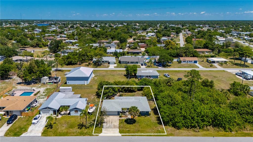 A blue single-story house features a white garage door, a pergola-covered patio, and landscaping — 540 GROVE AVENUE NW, PORT CHARLOTTE, FL