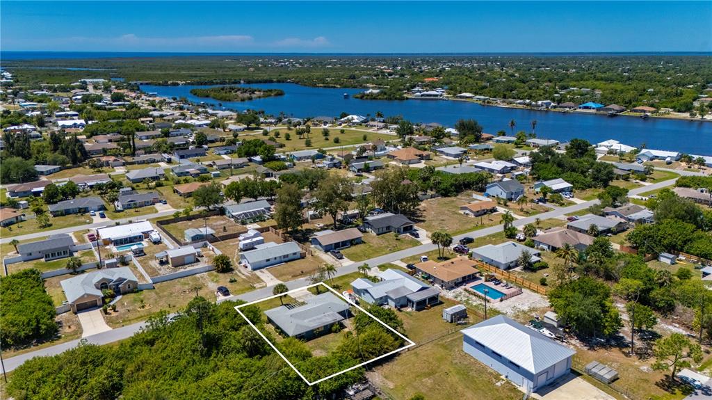 An aerial view shows a residential neighborhood with a highlighted house near a body of water — 540 GROVE AVENUE NW, PORT CHARLOTTE, FL