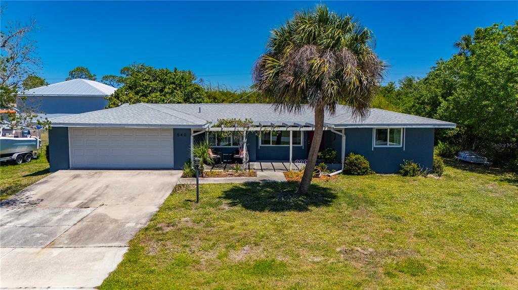 A single-story house with a gray exterior, a white garage door, and a palm tree — 540 GROVE AVENUE NW, PORT CHARLOTTE, FL