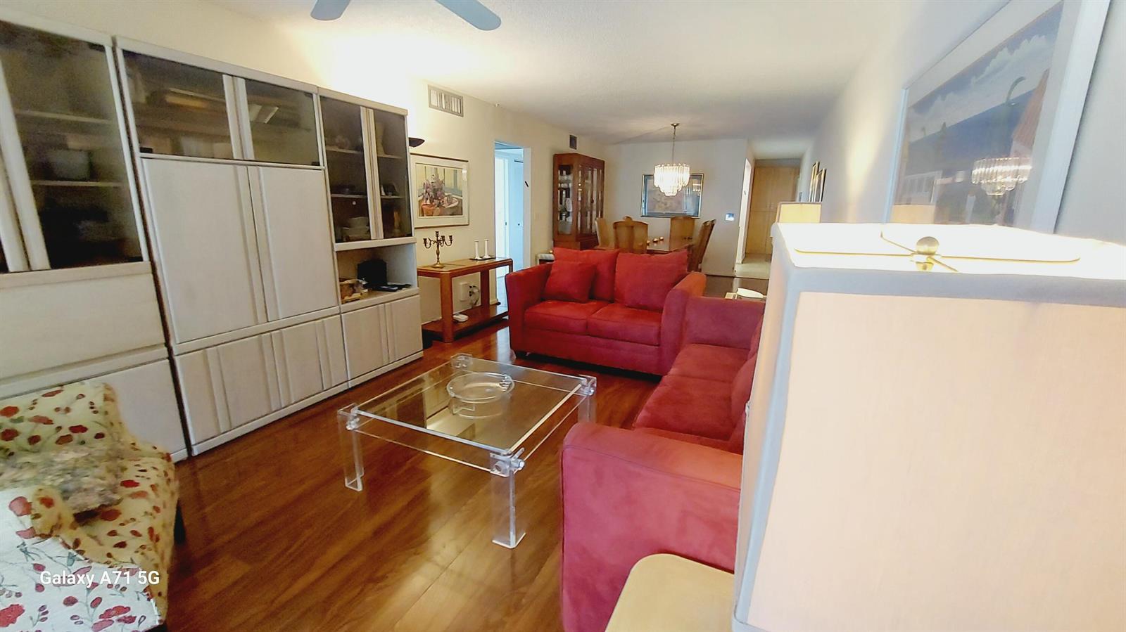 A living room features red sofas, a glass coffee table, and hardwood flooring — 2001 Yarmouth Drive # 2001, Boca Raton FL 33434, BOCA RATON, FL