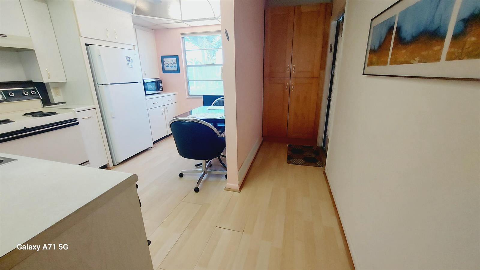 A kitchen with white cabinets, light wood-look flooring, and a small dining area — 2001 Yarmouth Drive # 2001, Boca Raton FL 33434, BOCA RATON, FL