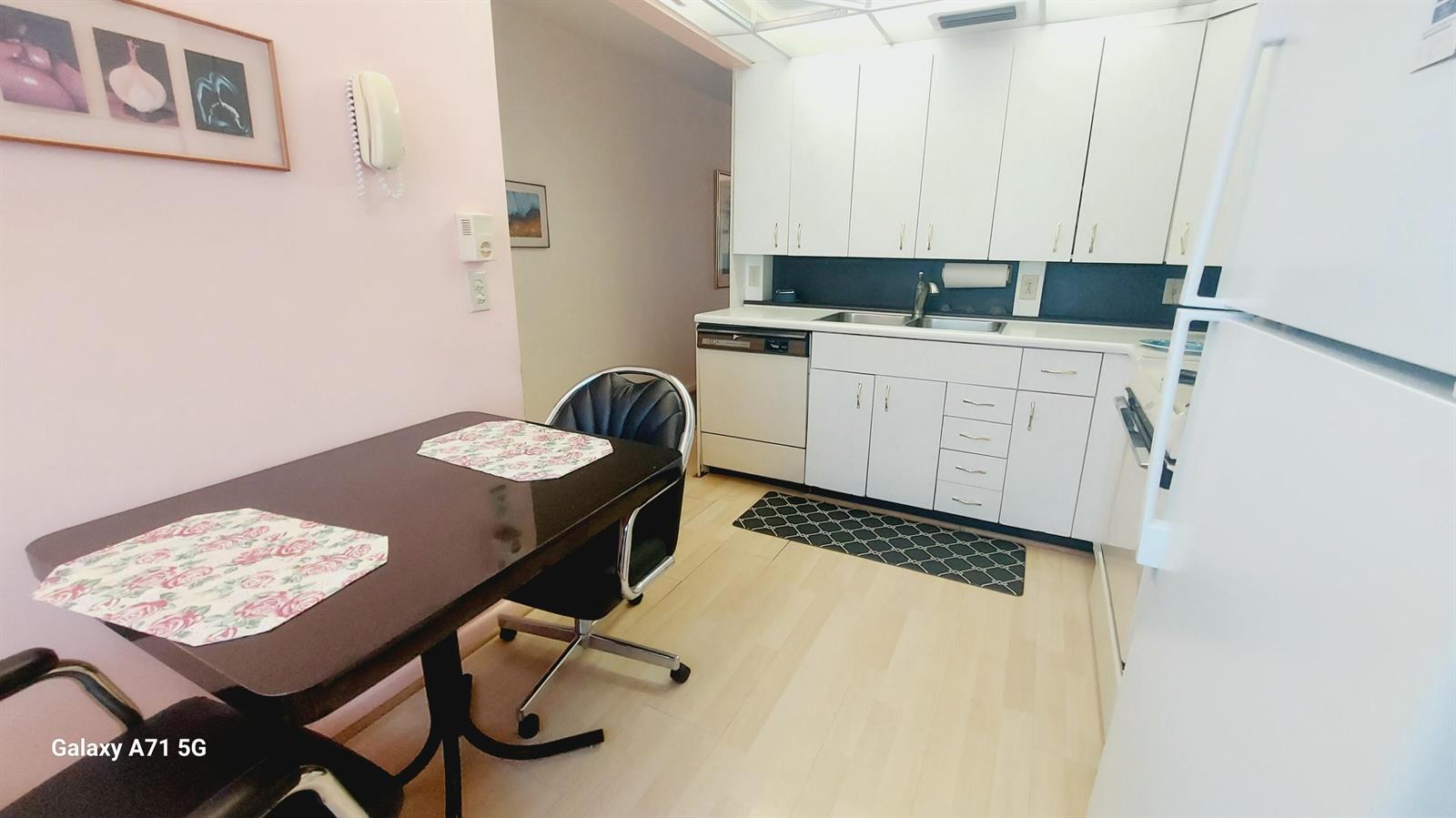 A kitchen with white cabinets, light wood flooring, and a dining table with chairs — 2001 Yarmouth Drive # 2001, Boca Raton FL 33434, BOCA RATON, FL