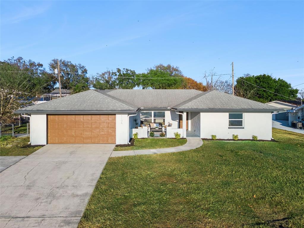 A single-story white house with a brown garage door and a concrete walkway — 1106 LAKE ARIANA BOULEVARD, AUBURNDALE, FL