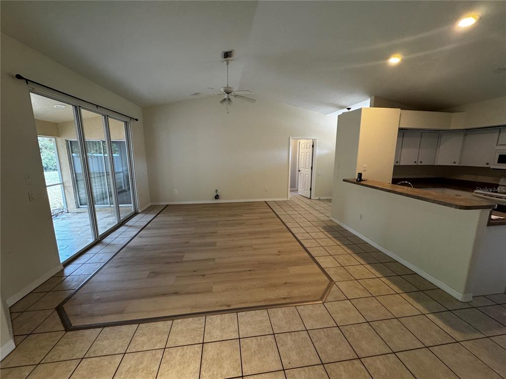 An open living area features a wood-look floor inlay surrounded by light-colored tile flooring — 8234 MOSSBORGER AVENUE, NORTH PORT, FL