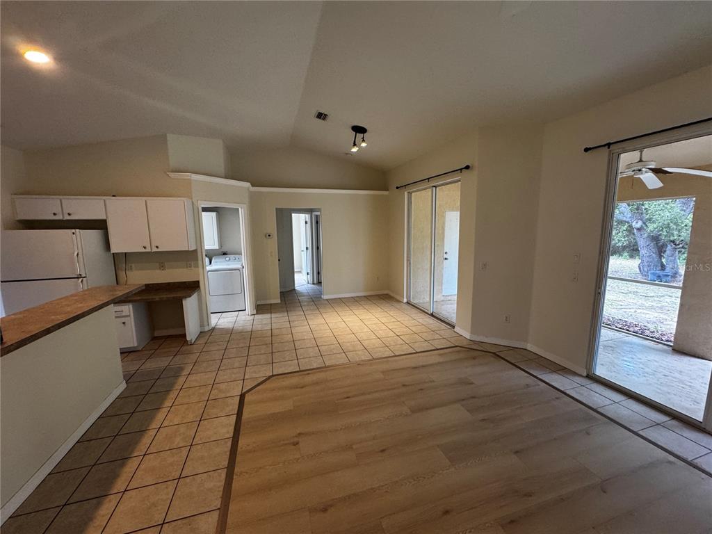 An open-concept kitchen and living area features tile and wood flooring with sliding glass doors — 8234 MOSSBORGER AVENUE, NORTH PORT, FL