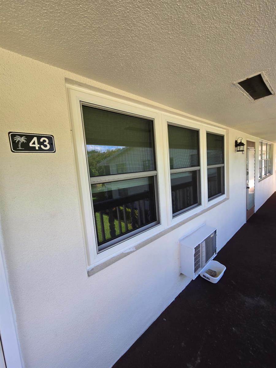 An exterior view of a building walkway featuring a window, an air conditioning unit, and unit 43 — 43 Markham B # 43, Deerfield Beach FL 33442, DEERFIELD BEACH, FL