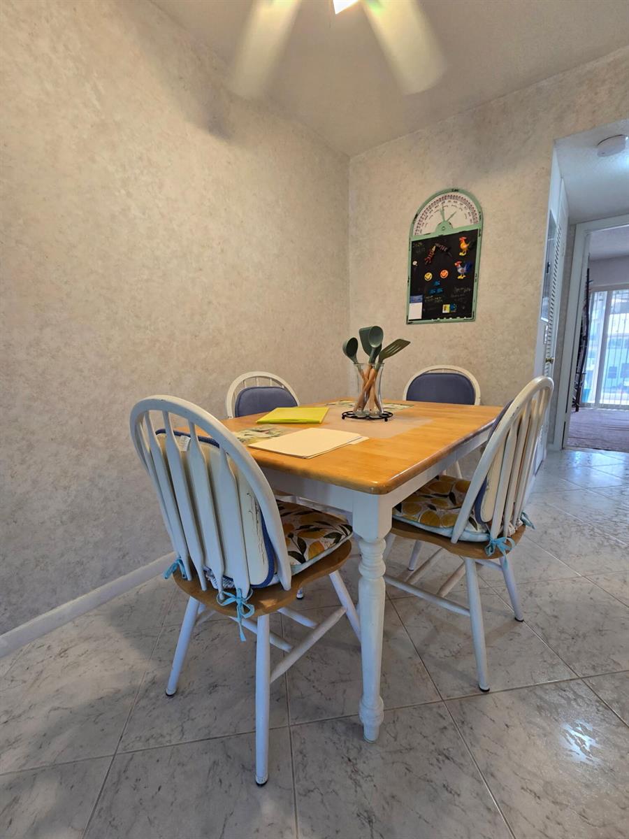 A dining area features a wooden table with four white chairs on a tiled floor — 43 Markham B # 43, Deerfield Beach FL 33442, DEERFIELD BEACH, FL