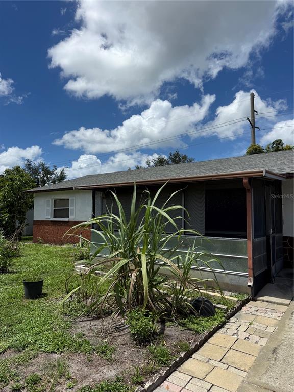 A single-story house exterior features a screened-in porch, a large plant, and a paved walkway — 3305 JOE LOUIS DRIVE, SARASOTA, FL
