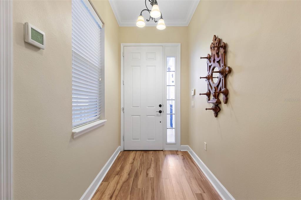 An entryway features wood-look flooring, a white front door with a sidelight, and wall-mounted decor — 200 RIVERFRONT DRIVE UNIT D201, PALM COAST, FL