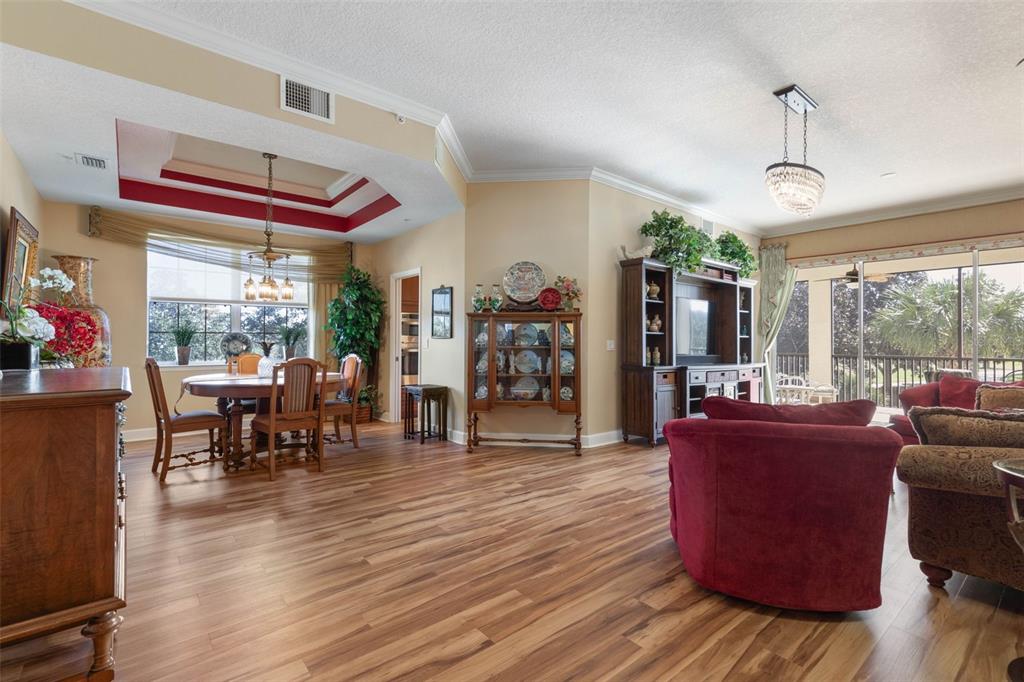 A living and dining area with wood-look flooring, a red tray ceiling, and sliding glass doors — 200 RIVERFRONT DRIVE UNIT D201, PALM COAST, FL