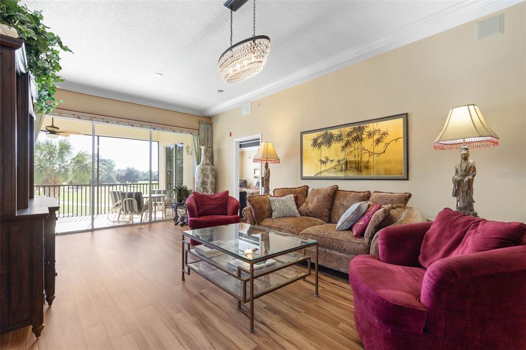 A living room features wood flooring, a glass coffee table, red armchairs, and a sofa — 200 RIVERFRONT DRIVE UNIT D201, PALM COAST, FL