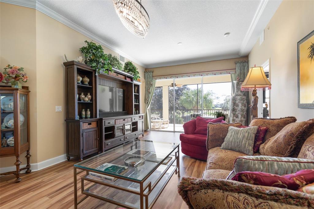 A living room features wood-look flooring, a large entertainment center, and a glass-topped coffee table — 200 RIVERFRONT DRIVE UNIT D201, PALM COAST, FL