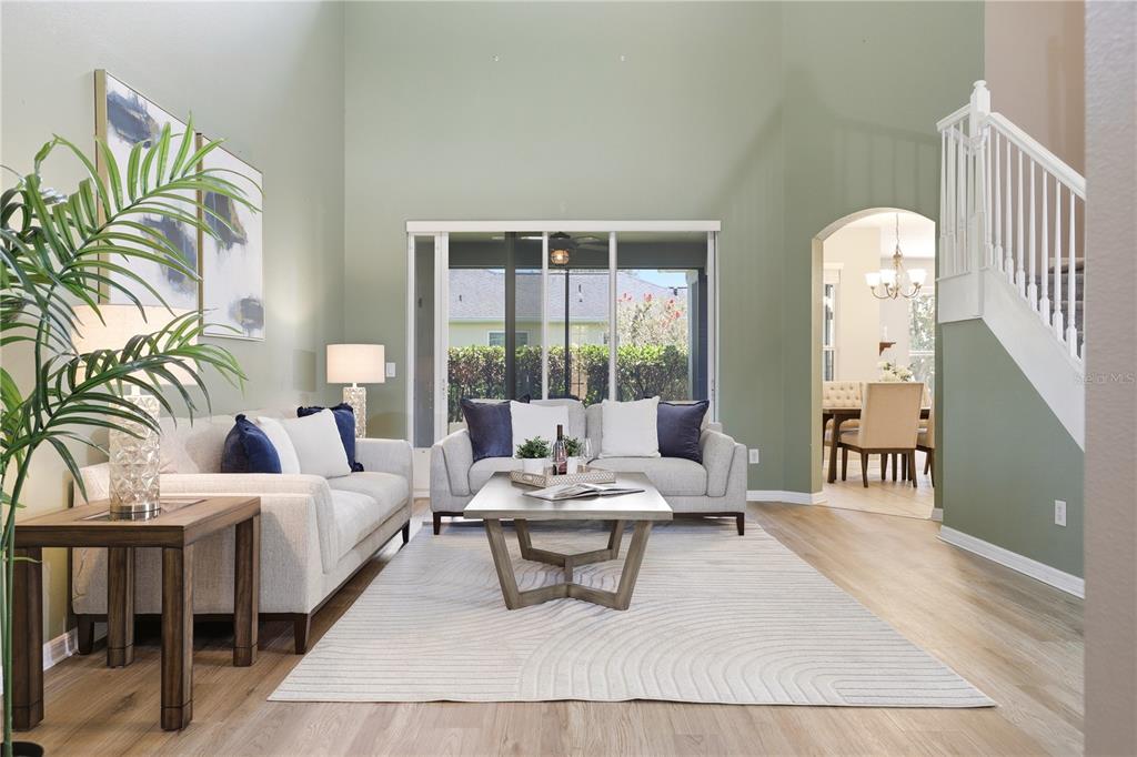 A living room features light-colored sofas, a central coffee table, and high ceilings — 3904 HEIRLOOM ROSE PLACE, OVIEDO, FL