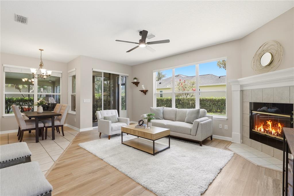 A living room with light wood floors, a fireplace, and an adjacent dining area — 3904 HEIRLOOM ROSE PLACE, OVIEDO, FL