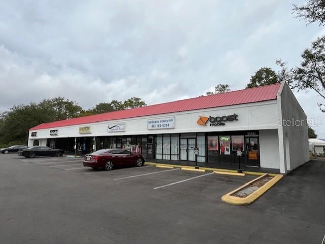A single-story commercial strip mall with a red metal roof and a paved parking lot — 37037 STATE ROAD 54, ZEPHYRHILLS, FL