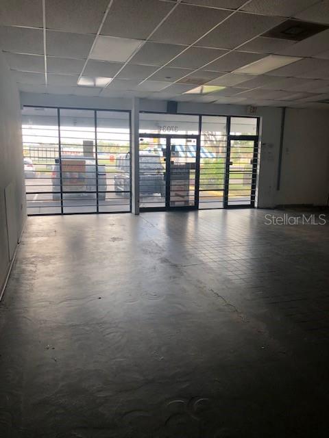 An empty commercial space with a drop ceiling, tiled floor, and large glass storefront windows — 37037 STATE ROAD 54, ZEPHYRHILLS, FL