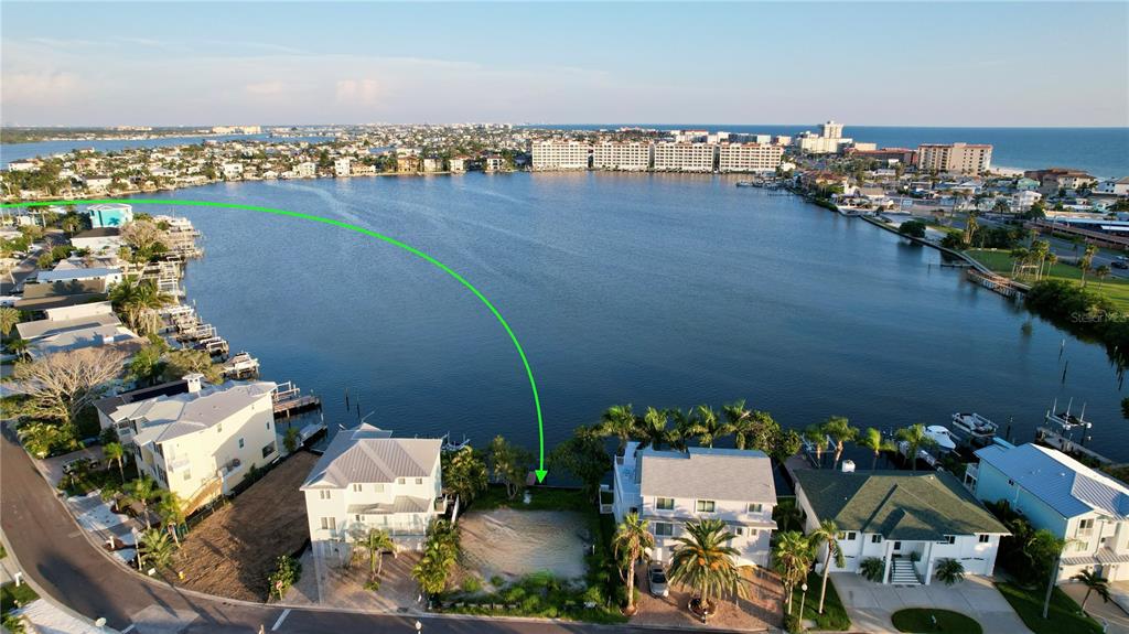 An aerial view shows a vacant waterfront lot situated between two houses on a bay — 415 180TH AVENUE E, REDINGTON SHORES, FL