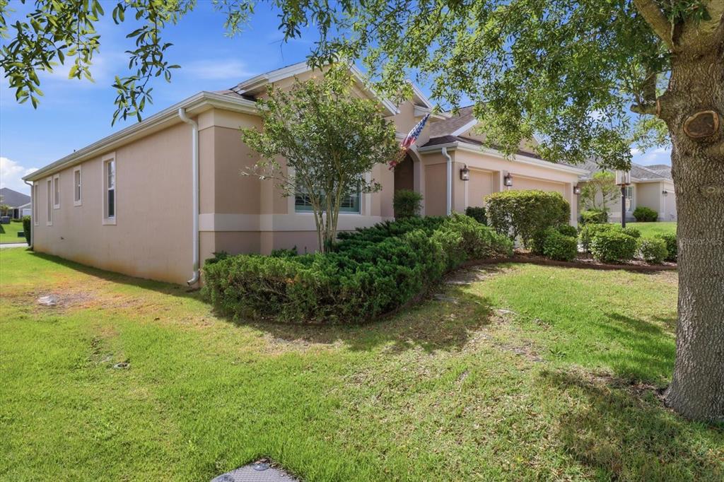 A tan, single-story house with a garage, a front lawn, and a large tree — 3087 BLACKSTOCK WAY, THE VILLAGES, FL