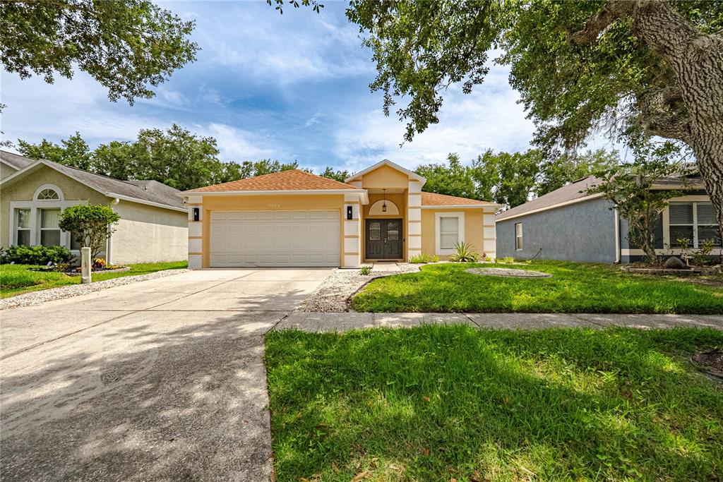 A single-story house with a yellow exterior, a two-car garage, and a concrete driveway — 19204 WOOD SAGE DRIVE, TAMPA, FL