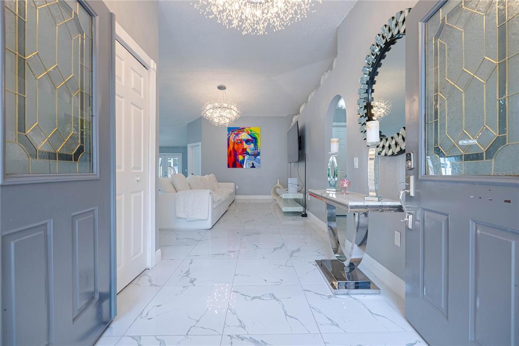 A bright entryway with white marble floors leads into a living room with modern decor — 19204 WOOD SAGE DRIVE, TAMPA, FL