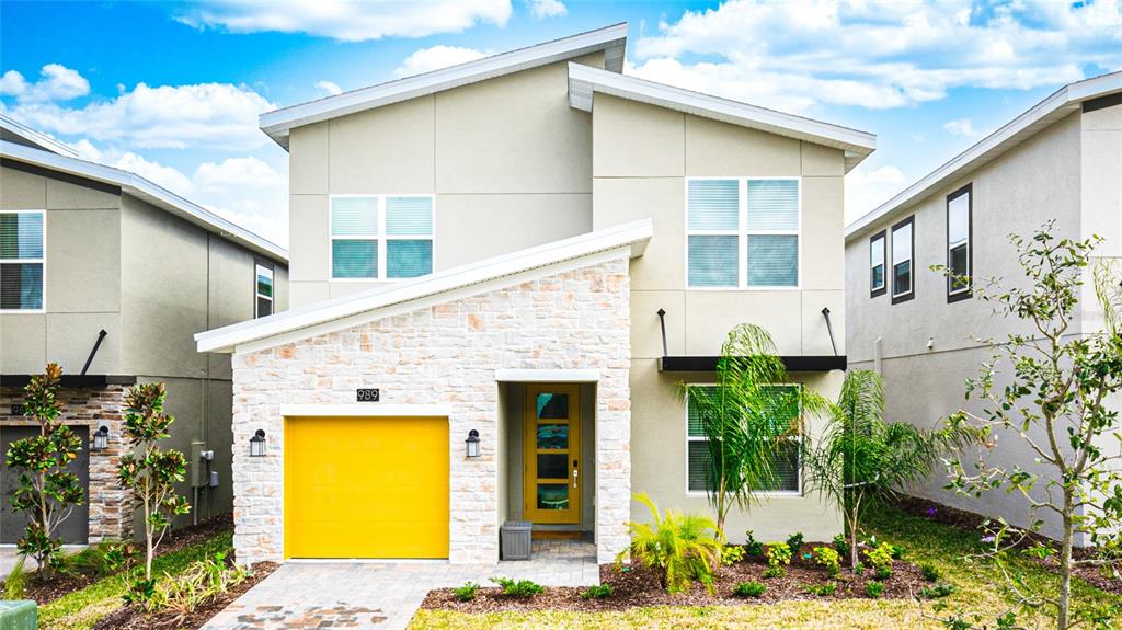 A two-story house features a yellow garage door, stone facade, and a yellow front door — 989 LEADER STREET, DAVENPORT, FL