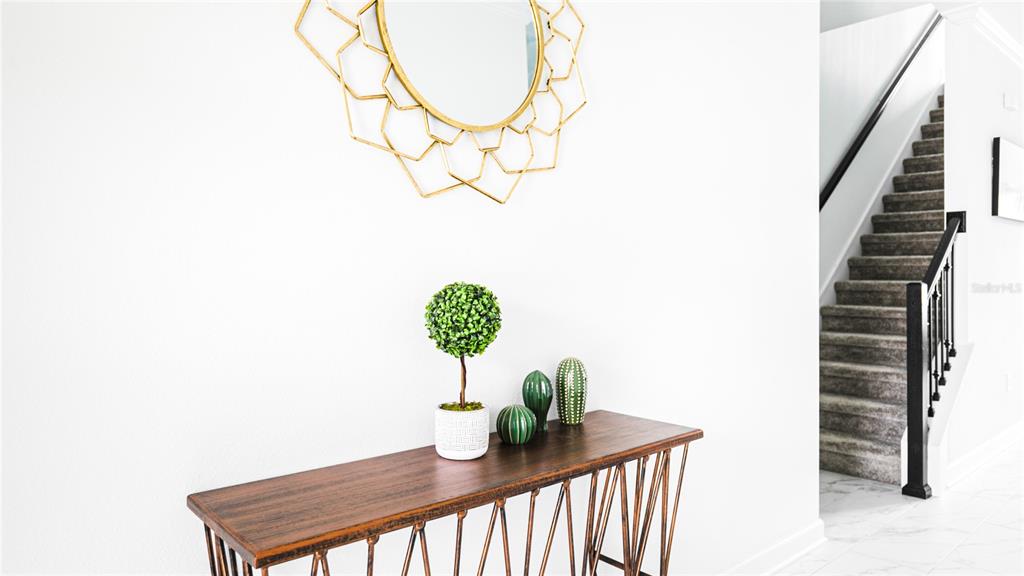 A wooden console table with decor sits in a white entryway near a staircase — 989 LEADER STREET, DAVENPORT, FL