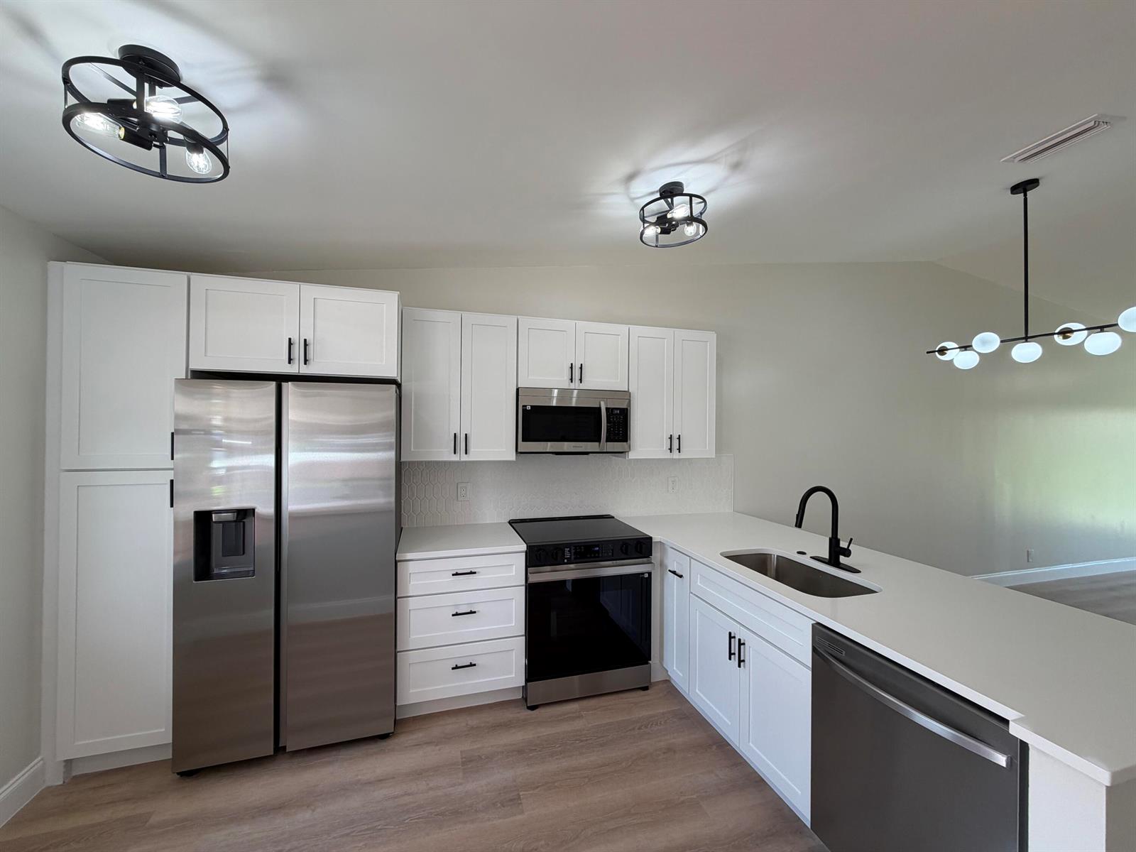 A modern kitchen features white cabinets, stainless steel appliances, and a white quartz countertop — 18720 Schooner Drive, Boca Raton FL 33496, BOCA RATON, FL