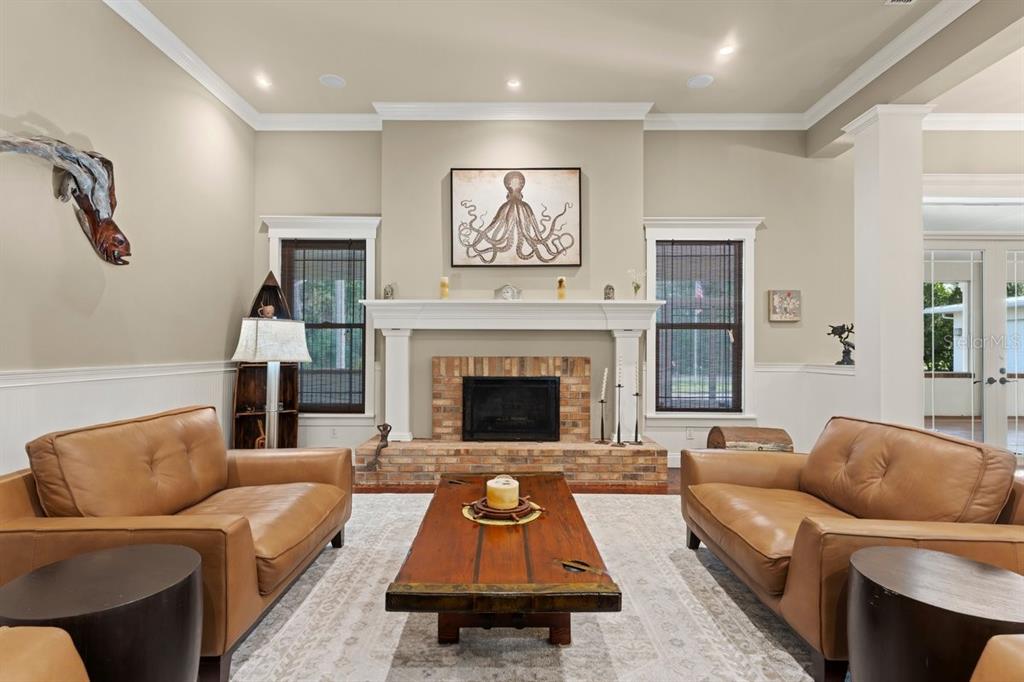 A living room features two leather sofas, a brick fireplace, and an octopus wall print — 2659 PIONEER TRAIL, NEW SMYRNA BEACH, FL
