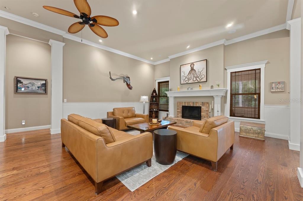 A living room features tan leather furniture, a fireplace, and a ceiling fan — 2659 PIONEER TRAIL, NEW SMYRNA BEACH, FL