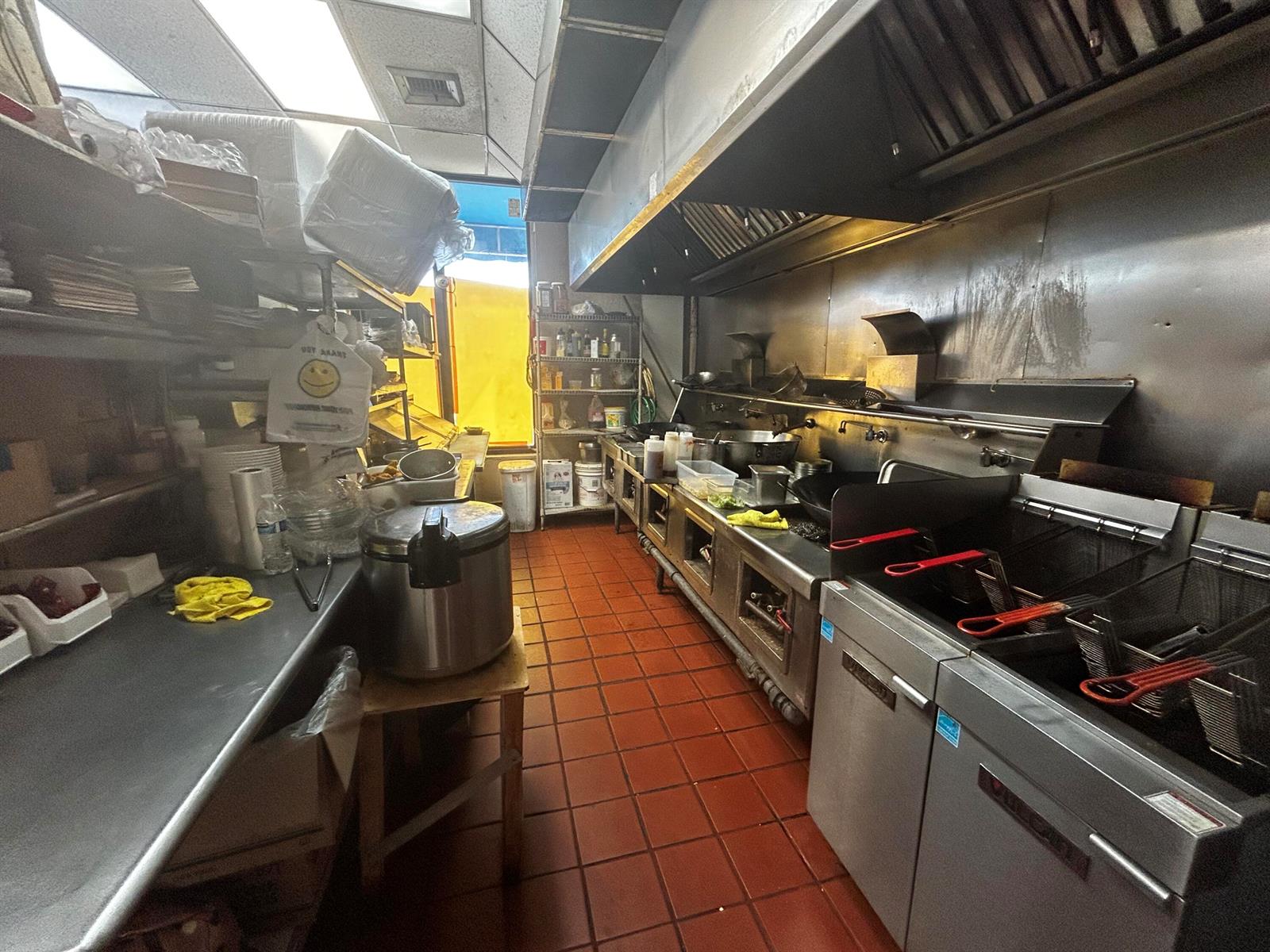 A commercial kitchen features stainless steel appliances, a deep fryer, and red tile flooring — 2623 W Atlantic Boulevard, Pompano Beach FL 33069, POMPANO BEACH, FL
