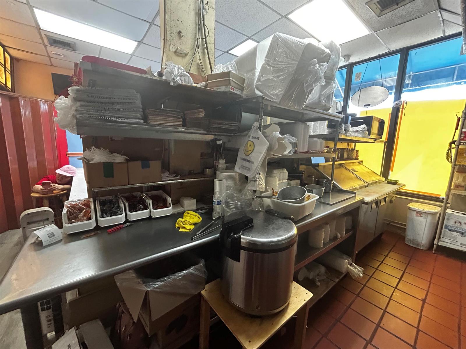 A commercial kitchen features stainless steel counters, shelving, food containers, and a large rice cooker — 2623 W Atlantic Boulevard, Pompano Beach FL 33069, POMPANO BEACH, FL