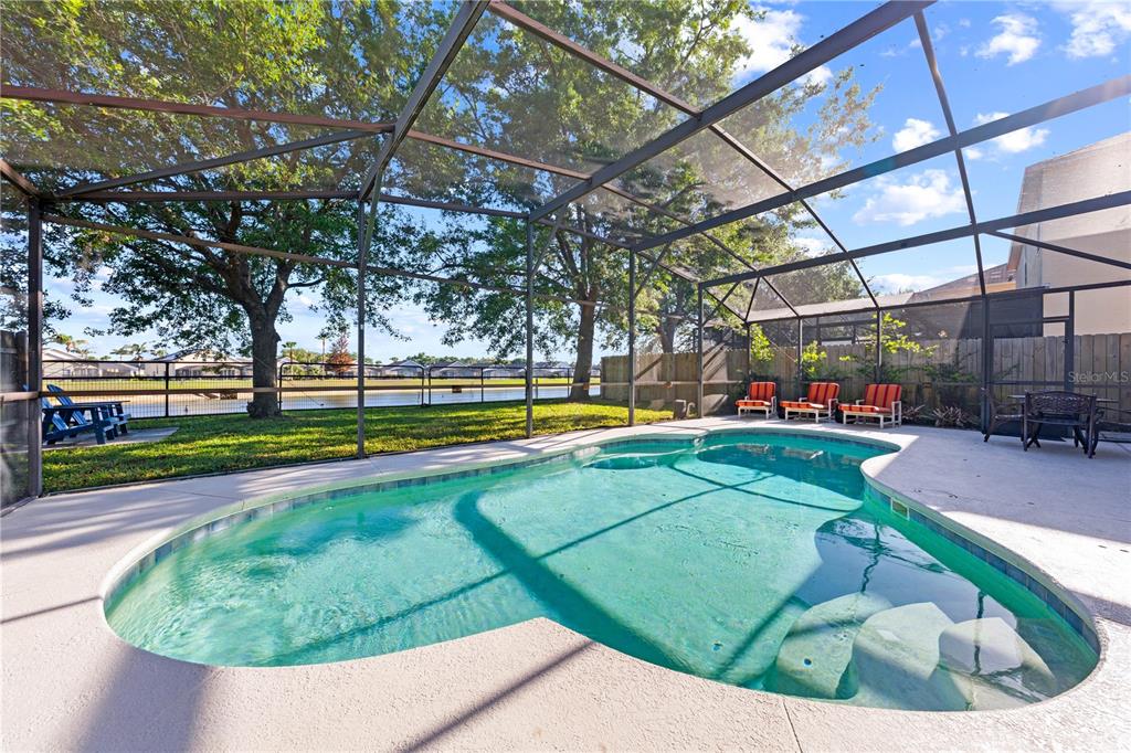 A screened-in swimming pool with a patio and lounge chairs overlooks a lake — 16641 SUNRISE VISTA DRIVE, CLERMONT, FL