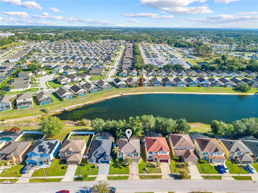 An aerial view shows a suburban neighborhood with houses bordering a lake — 16641 SUNRISE VISTA DRIVE, CLERMONT, FL