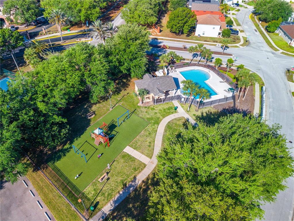 An aerial view shows a community playground and swimming pool area surrounded by lush trees — 16641 SUNRISE VISTA DRIVE, CLERMONT, FL
