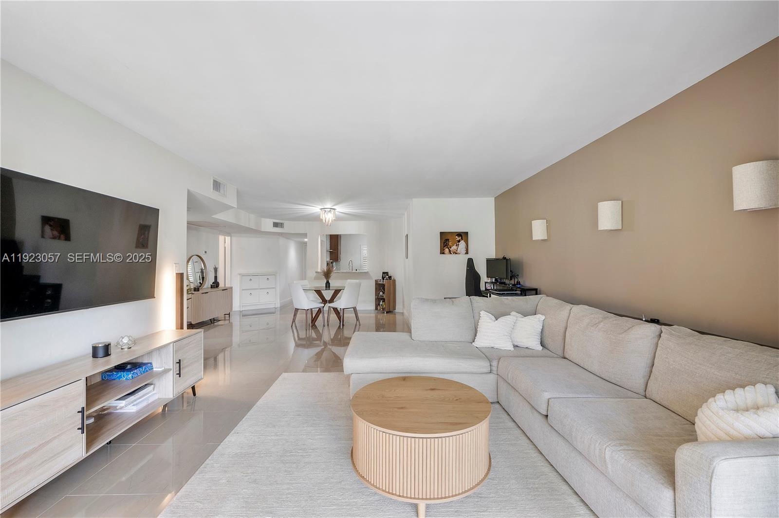A living room features a sectional sofa, a round coffee table, and a wall-mounted television — 1706 Hammock Blvd # 1706, Coconut Creek FL 33063, COCONUT CREEK, FL