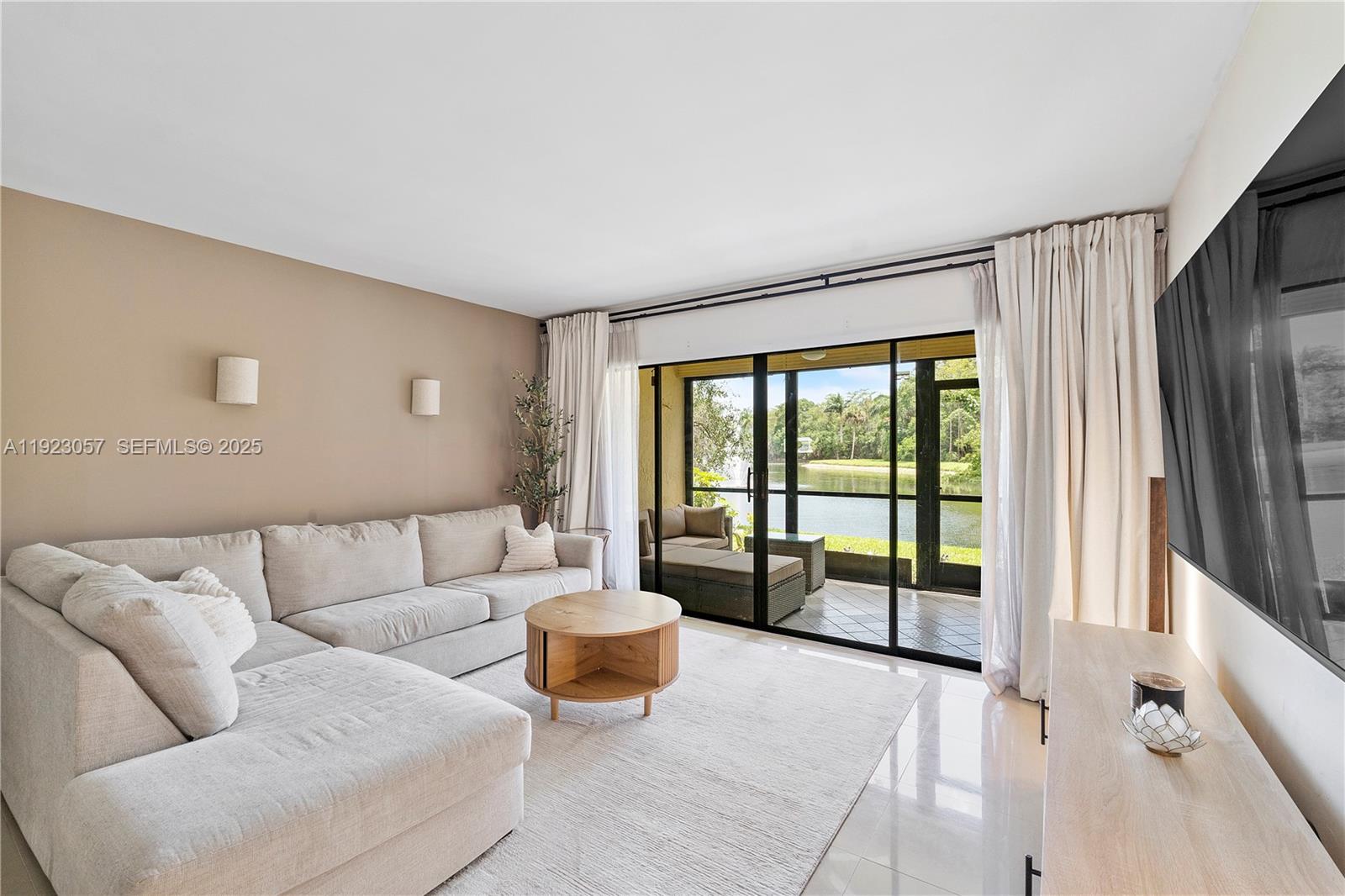 A living room features a sectional sofa, a round coffee table, and sliding glass doors — 1706 Hammock Blvd # 1706, Coconut Creek FL 33063, COCONUT CREEK, FL