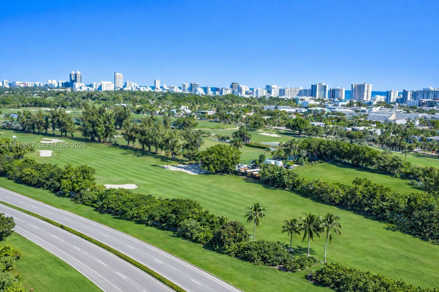 An aerial view shows a golf course adjacent to a road with a city skyline — 2050 Alton Rd, Miami Beach FL 33140, MIAMI BEACH, FL