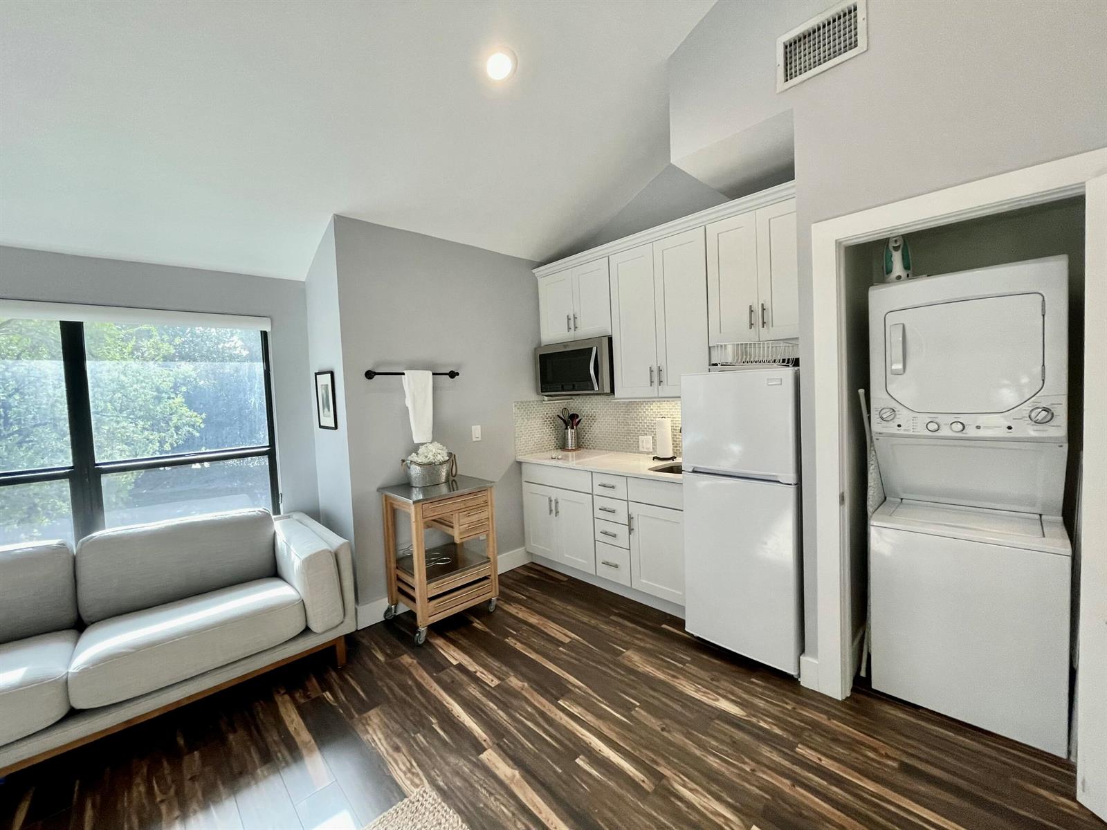 A small kitchen area features white cabinets, a refrigerator, and a stacked washer-dryer unit — 11863 Wimbledon Circle # 547, Wellington FL 33414, WELLINGTON, FL