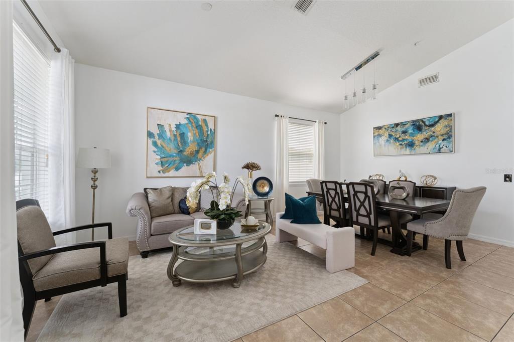 A living and dining area features tile floors, neutral furniture, and blue and gold wall art — 10484 EASTPARK LAKE DRIVE, ORLANDO, FL