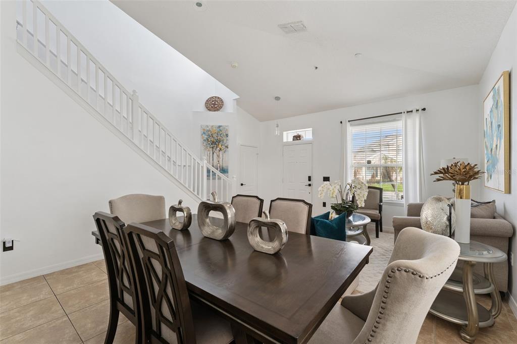A dining area with a dark wood table and chairs sits before a staircase — 10484 EASTPARK LAKE DRIVE, ORLANDO, FL