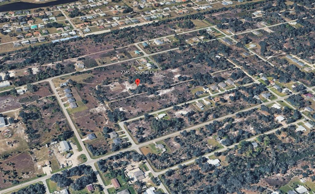 An aerial view shows a vacant, wooded residential lot marked with a red location pin — 2345 DIPLOMAT DRIVE, PUNTA GORDA, FL