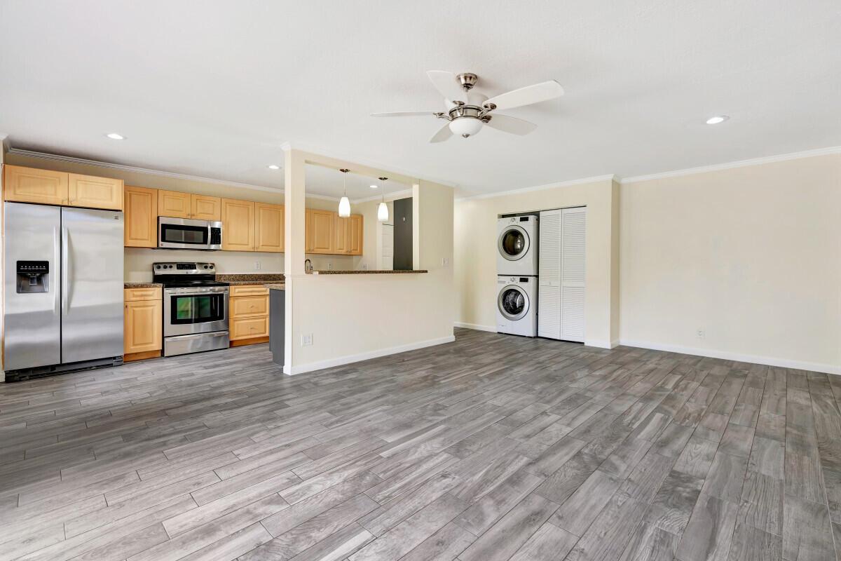 A kitchen with light wood cabinets and stainless steel appliances opens to a living area — 150 Pineview Road # F3, Jupiter FL 33469, JUPITER, FL