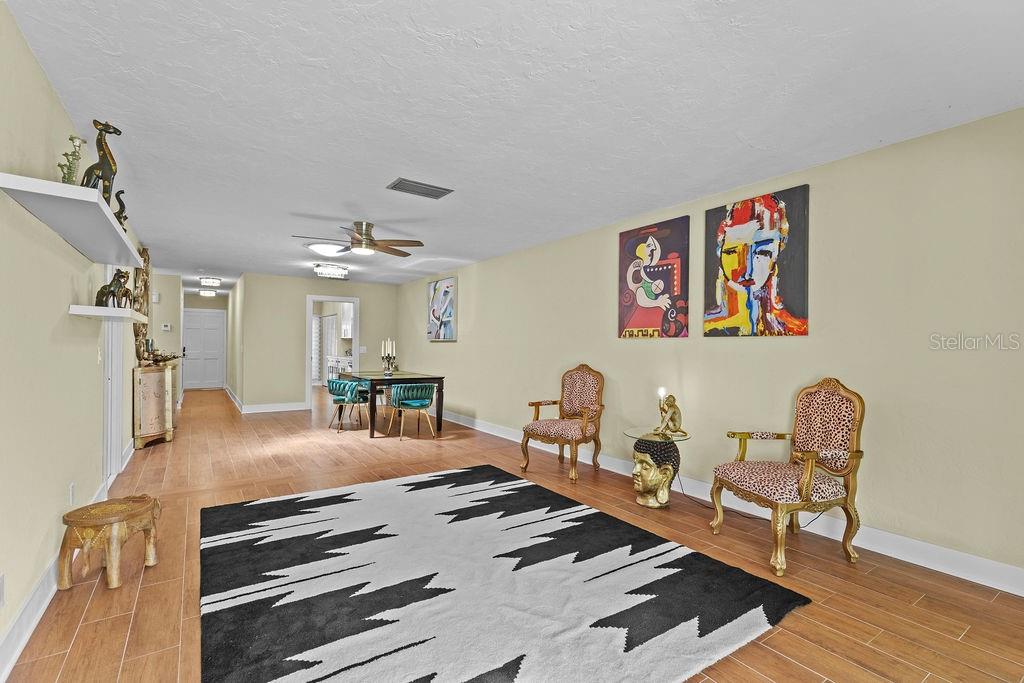 A living and dining area features wood-look tile floors, a patterned rug, and wall art — 215 BOCA CIEGA POINT BOULEVARD N UNIT 3, ST PETERSBURG, FL