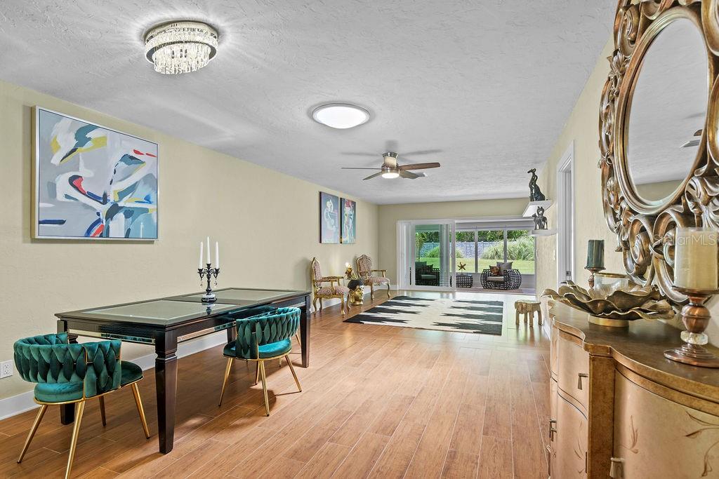 A dining area with a glass-topped table and teal chairs opens into a living space — 215 BOCA CIEGA POINT BOULEVARD N UNIT 3, ST PETERSBURG, FL